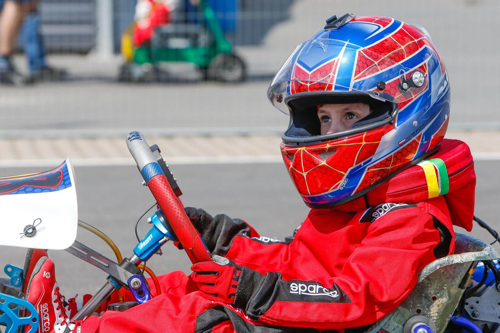Igor Ponichtera gotowy do jazdy - siedzący w gokarcie - w kasku i kombinezonie